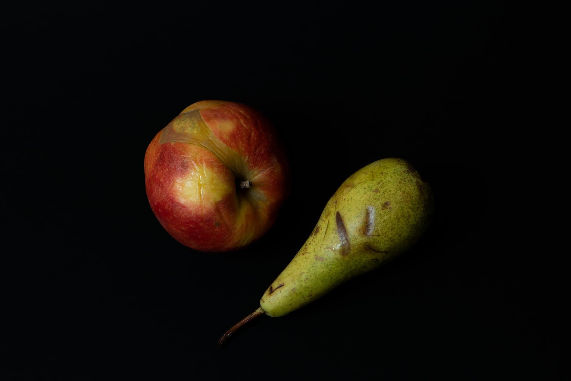 An apple and a pear on pure black background